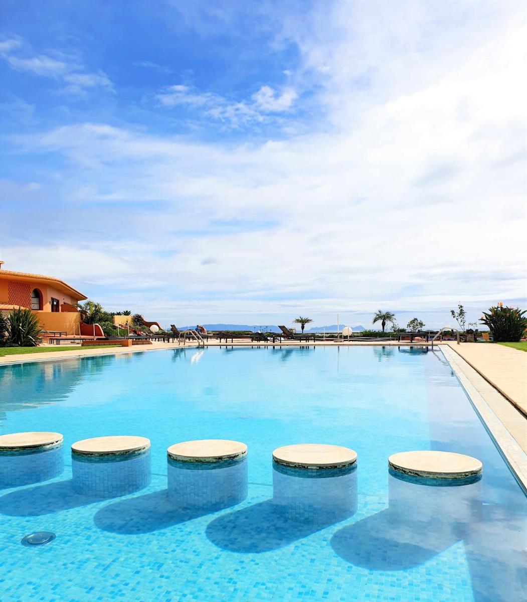 uma grande piscina com quatro bancos na água em Quinta Splendida Wellness & Botanical Garden no Caniço