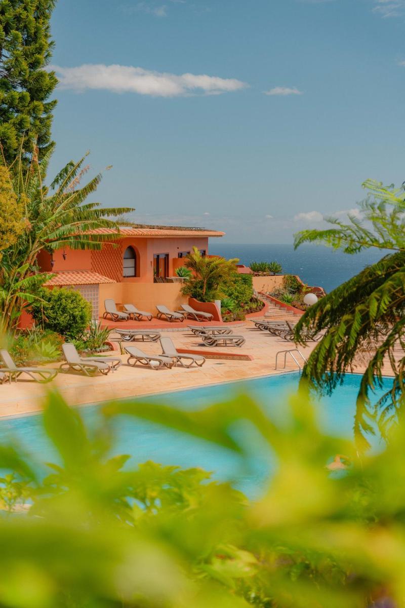 um resort com piscina, cadeiras e o oceano em Quinta Splendida Wellness & Botanical Garden no Caniço