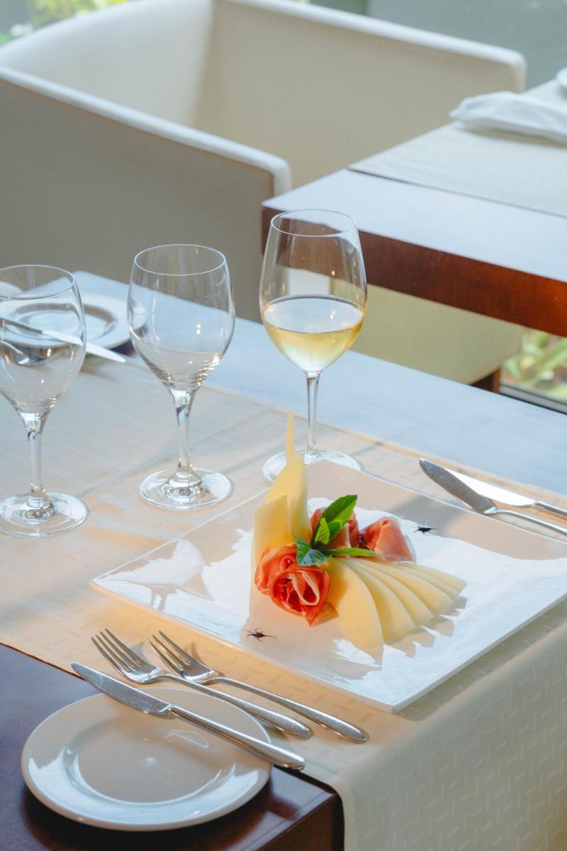 uma mesa com um prato de comida e copos de vinho em Quinta Splendida Wellness & Botanical Garden no Caniço