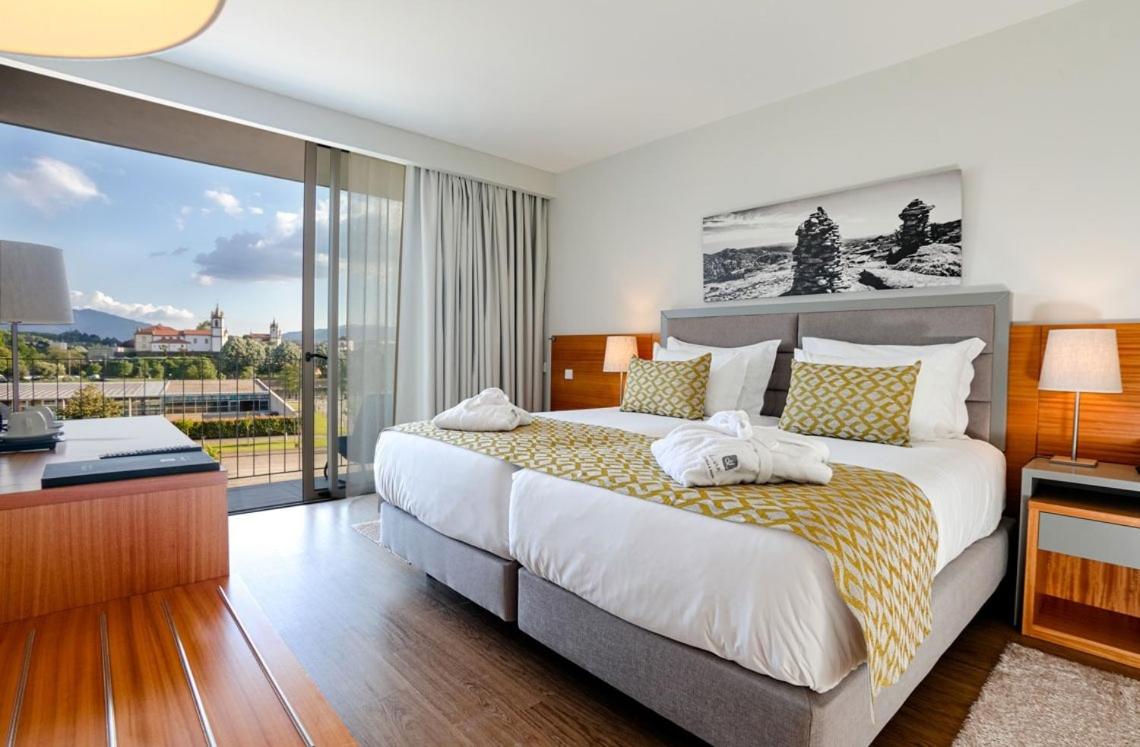 um quarto com uma cama grande e uma varanda em Luna Arcos Hotel Nature & Wellness em Arcos de Valdevez