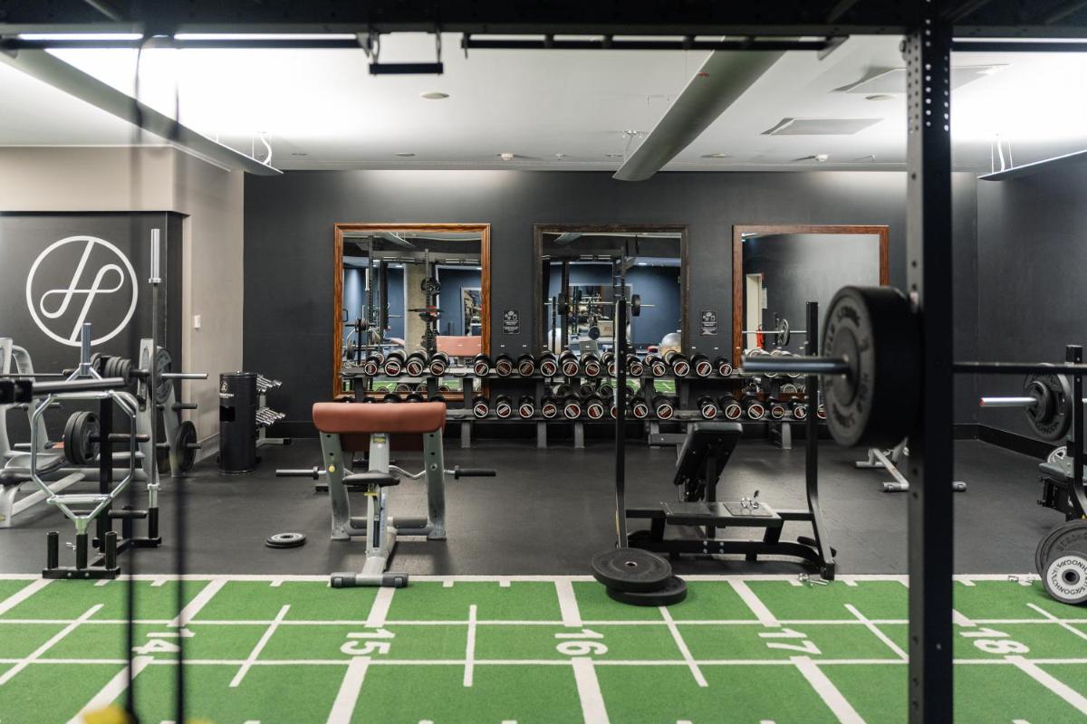 Ein Fitnessstudio mit Hanteln und Geräten auf grünem Boden in der Unterkunft Hotel Kö59 Düsseldorf - Member of Hommage Luxury Hotels Collection in Düsseldorf
