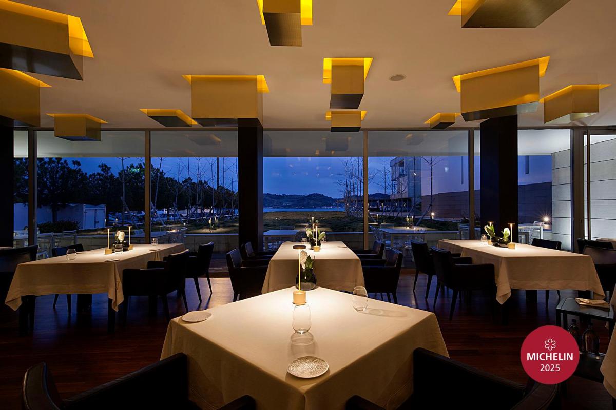 um restaurante com mesas, cadeiras e janelas em Altis Belem Hotel & Spa, a Member of Design Hotels em Lisboa