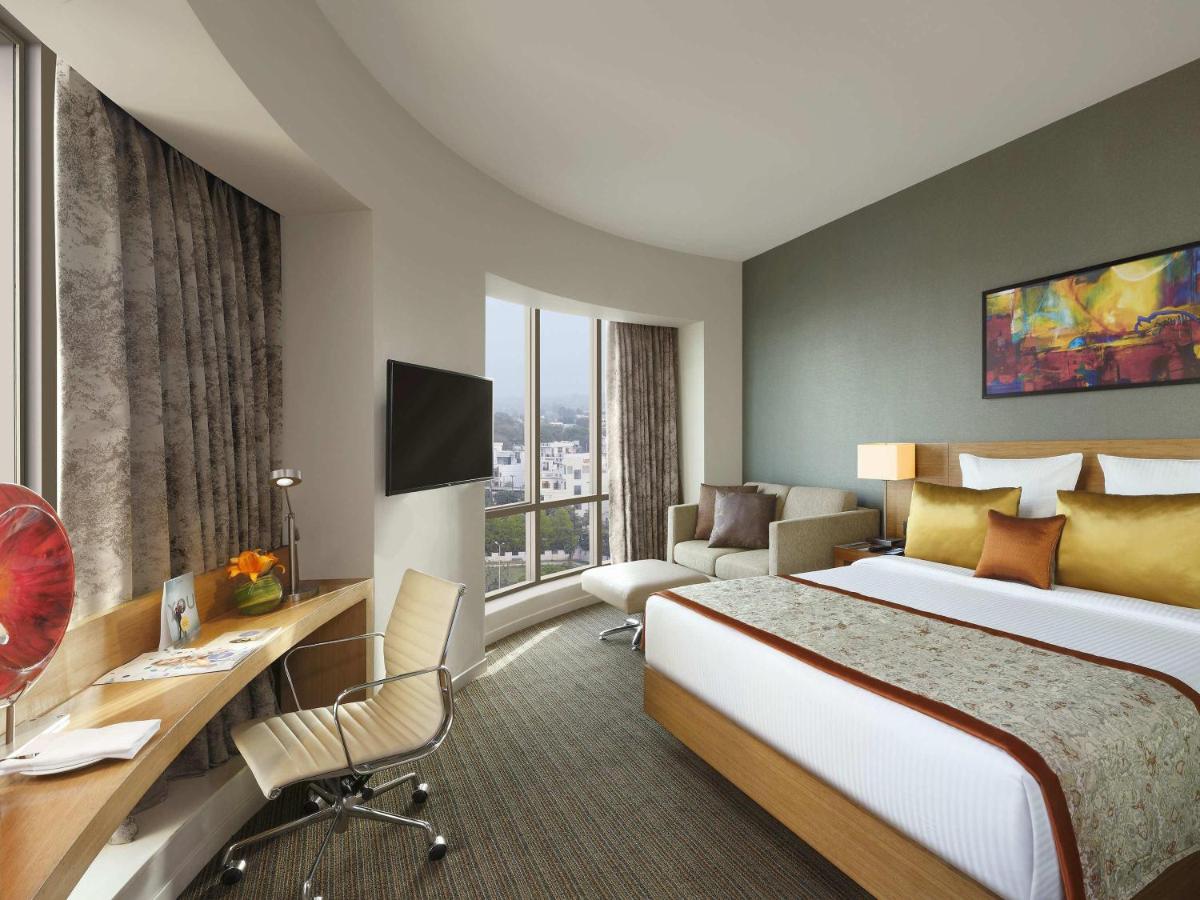 a hotel room with a large bed and a desk at Novotel Lucknow Gomti Nagar in Lucknow