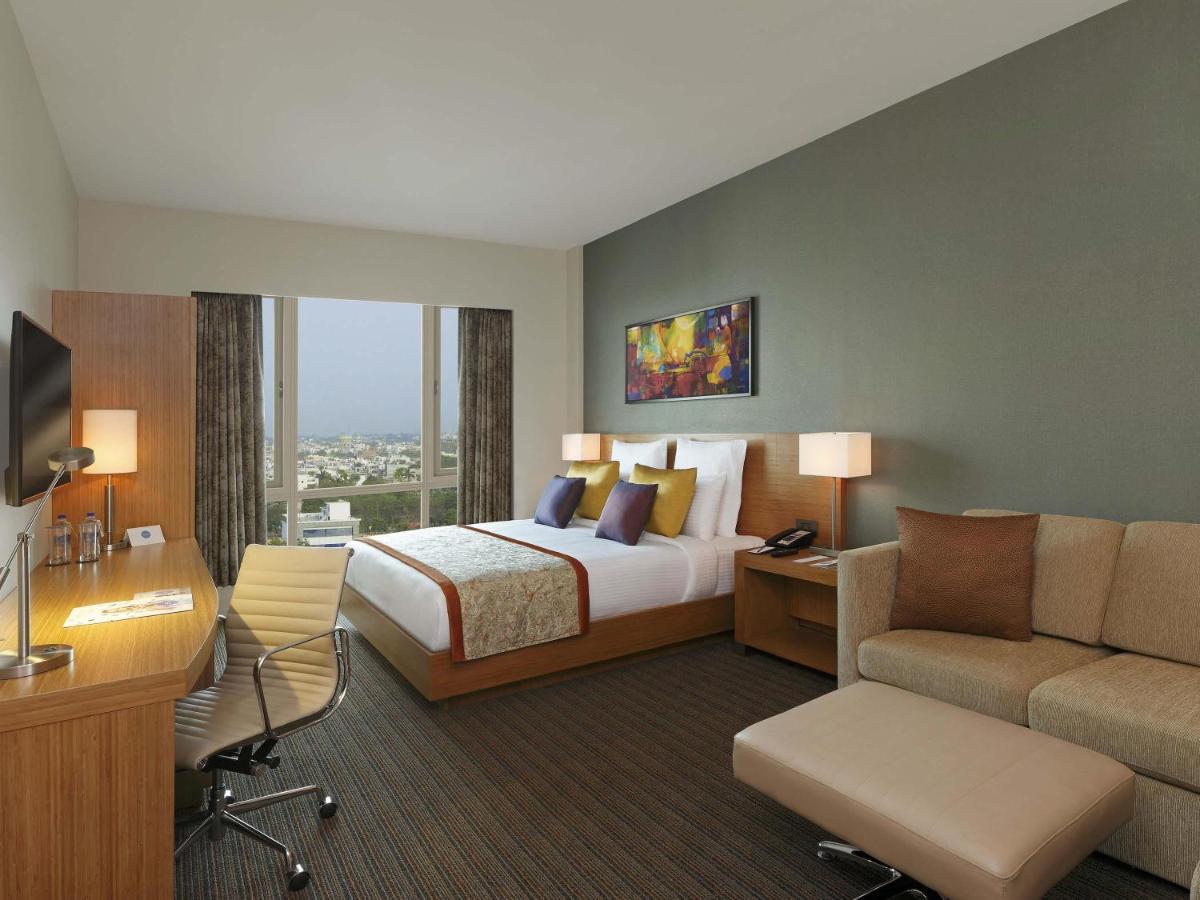 a hotel room with a bed and a desk and a couch at Novotel Lucknow Gomti Nagar in Lucknow