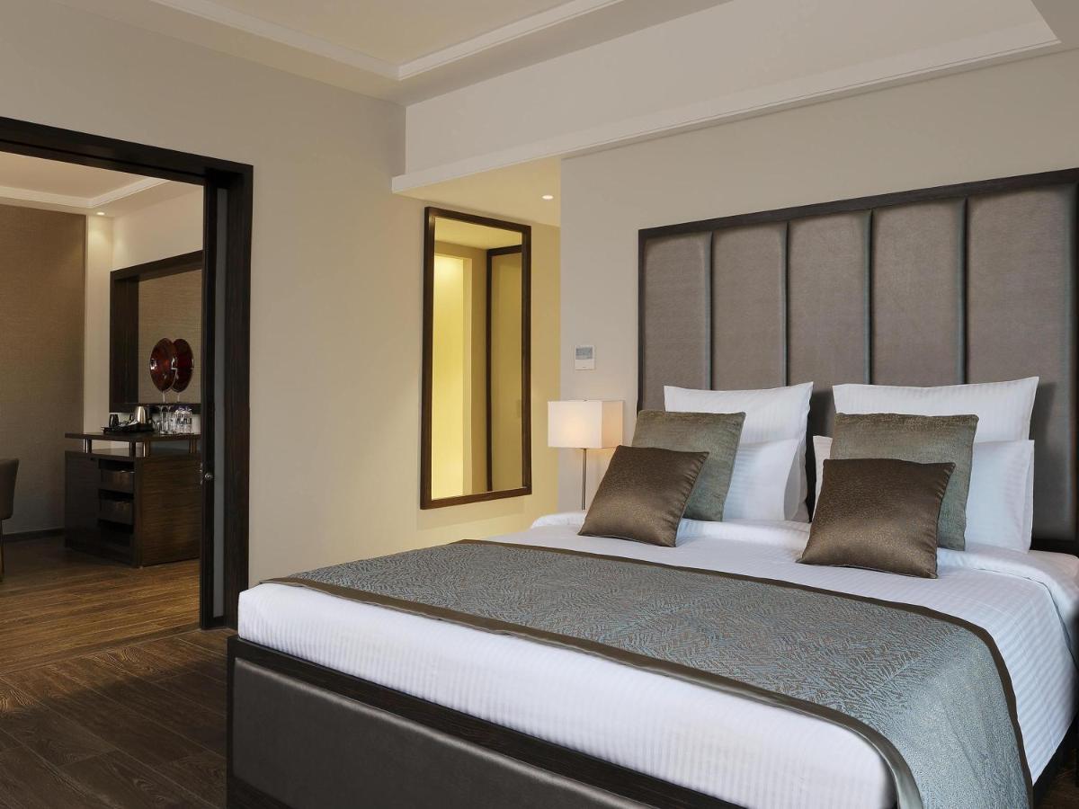 a bedroom with a large bed with a large headboard at Novotel Lucknow Gomti Nagar in Lucknow