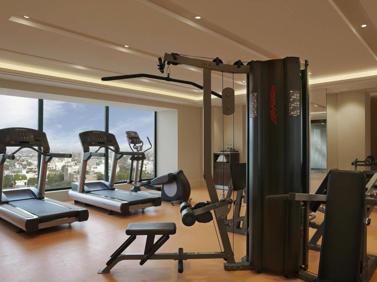 a gym with several exercise equipment in a room at Novotel Lucknow Gomti Nagar in Lucknow