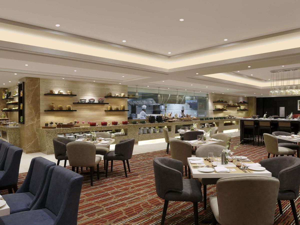 a restaurant with tables and chairs and a bar at Novotel Lucknow Gomti Nagar in Lucknow
