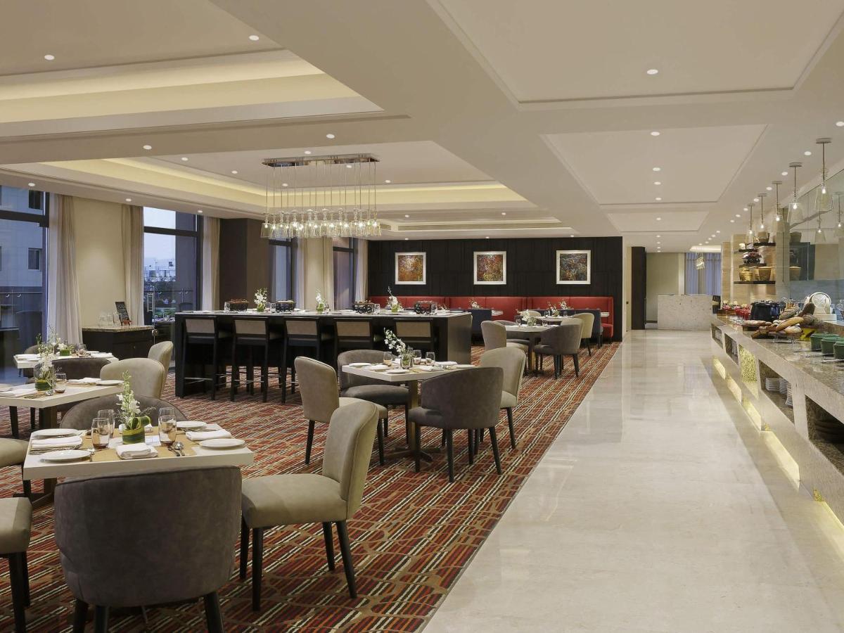 a restaurant with tables and chairs and a bar at Novotel Lucknow Gomti Nagar in Lucknow