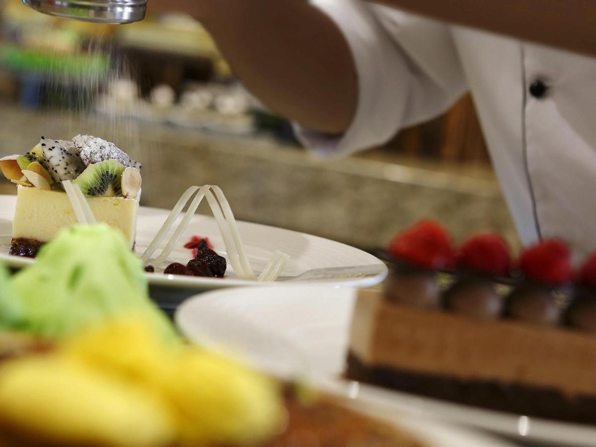 a person is preparing a dessert on a plate at Novotel Lucknow Gomti Nagar in Lucknow