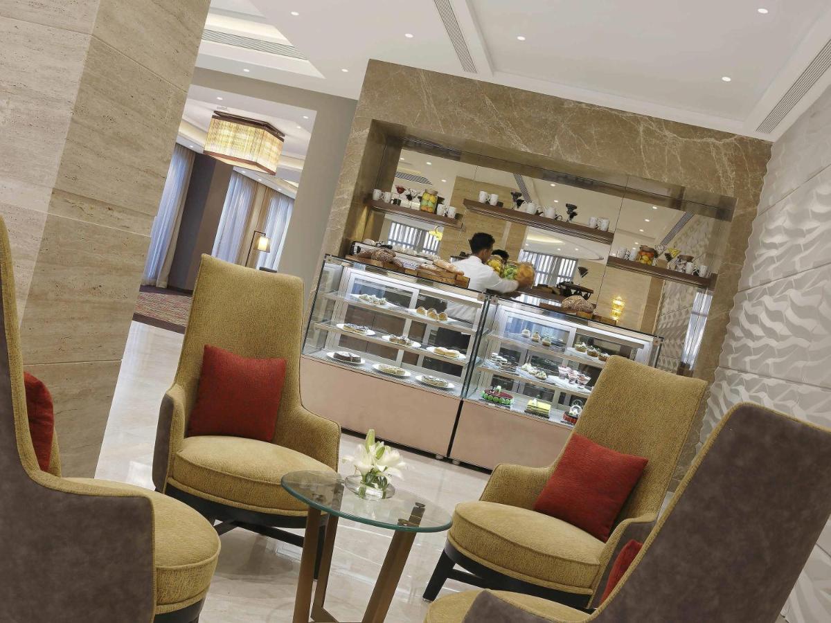 a restaurant with chairs and a table and a counter at Novotel Lucknow Gomti Nagar in Lucknow