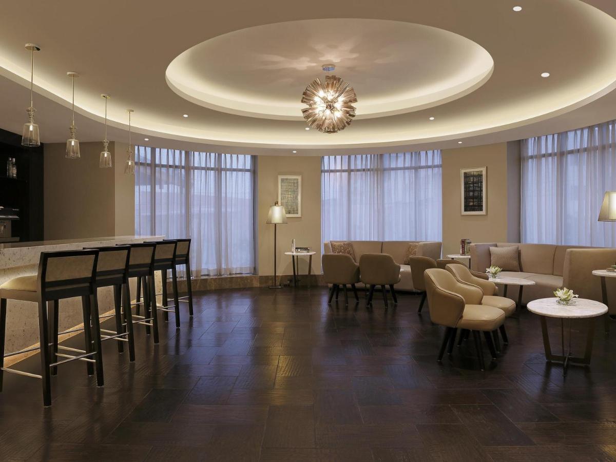 a waiting room with tables and chairs and a chandelier at Novotel Lucknow Gomti Nagar in Lucknow