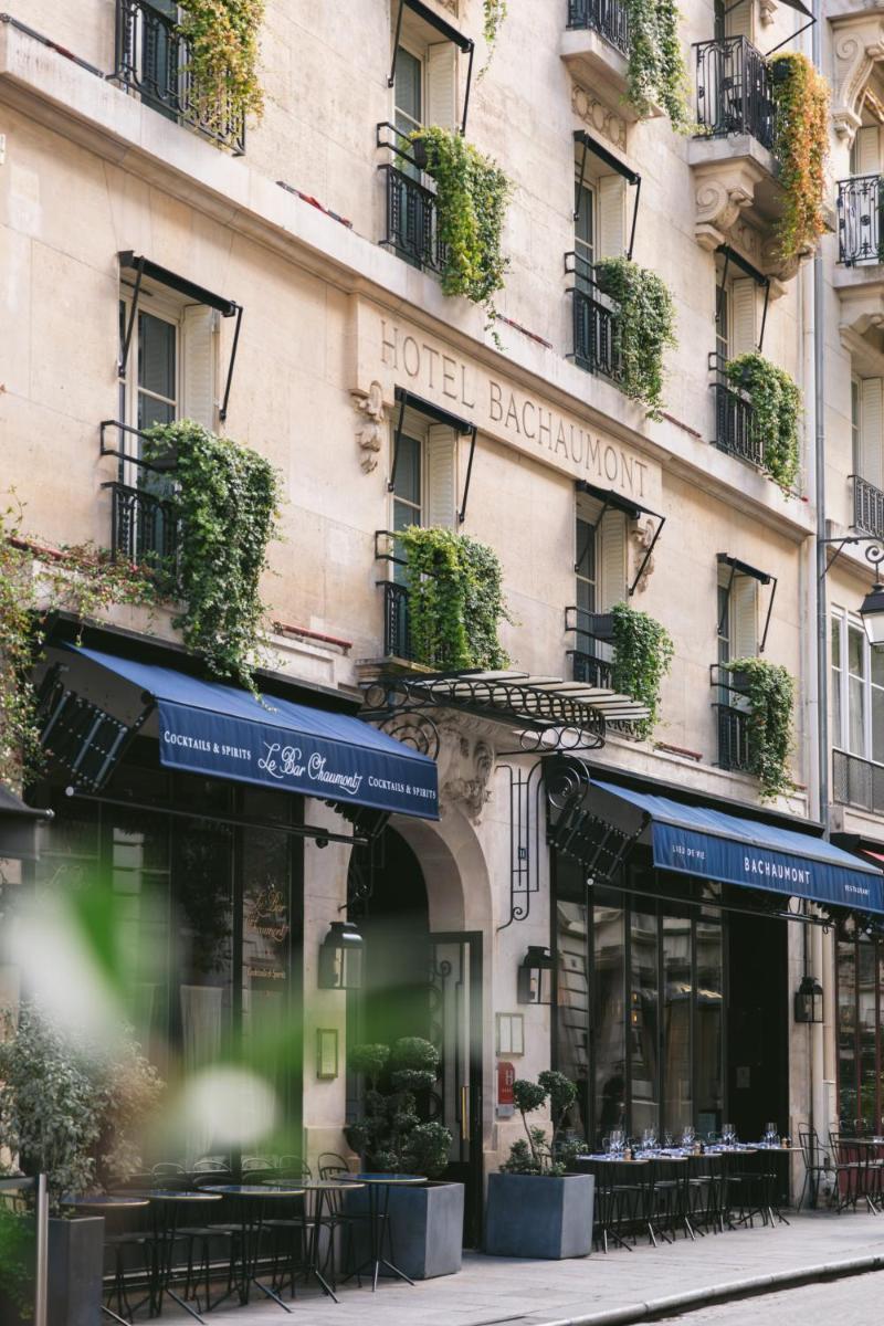 un bâtiment avec des tables et des chaises devant lui dans l'établissement Hotel Bachaumont, à Paris