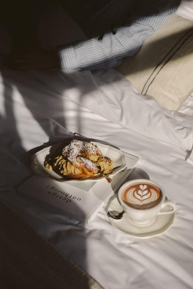 - une assiette de nourriture et une tasse de café sur le lit dans l'établissement Hotel Bachaumont, à Paris