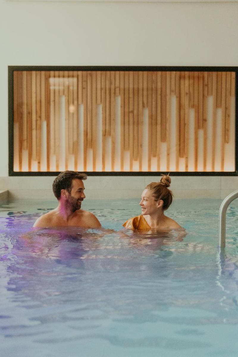 un homme et une femme dans une piscine dans l'établissement Demeures de Campagne Parc du Coudray - Barbizon, à Le Coudray-Montceaux