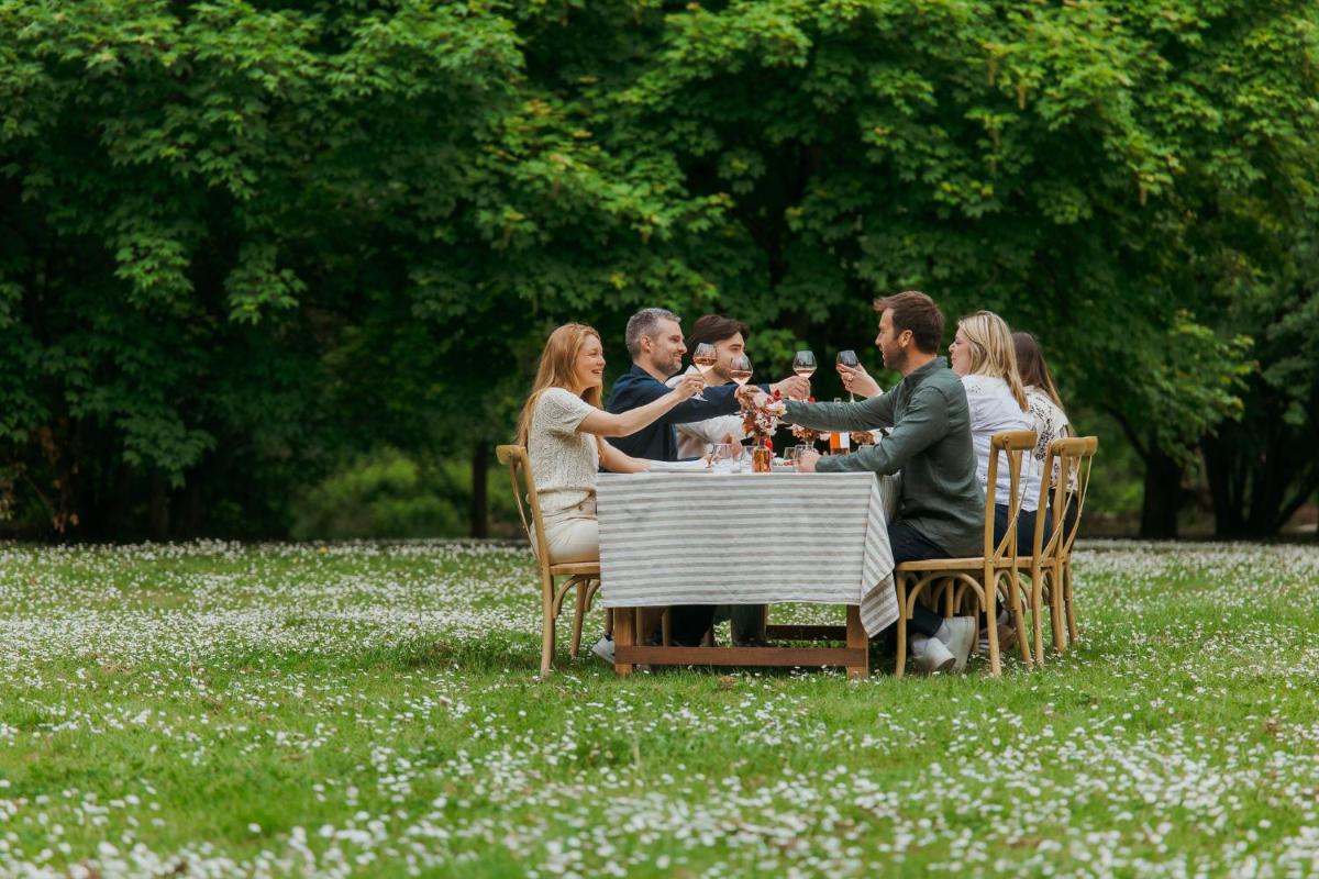un groupe de personnes assis à table en train de boire du vin dans l'établissement Demeures de Campagne Parc du Coudray - Barbizon, à Le Coudray-Montceaux