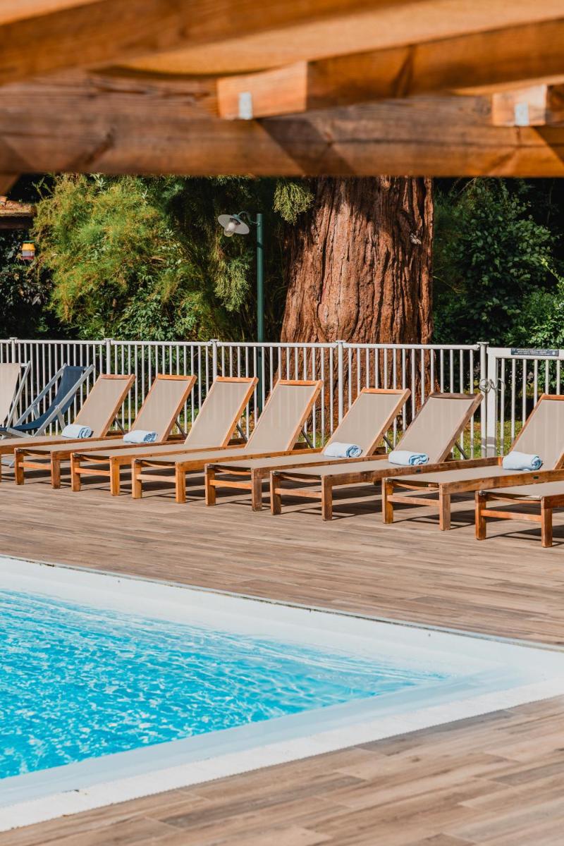 une rangée de chaises longues à côté d'une piscine dans l'établissement Demeures de Campagne Parc du Coudray - Barbizon, à Le Coudray-Montceaux