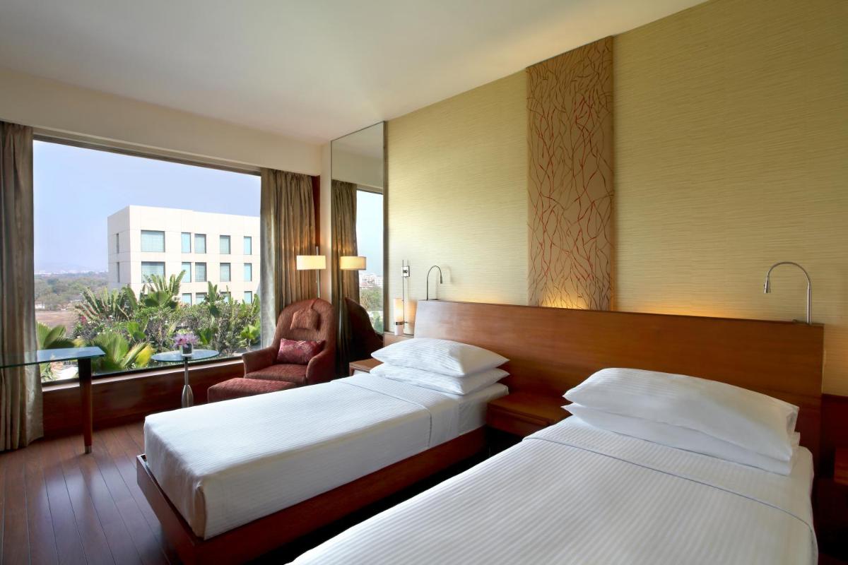 a hotel room with two beds and a window at Hyatt Pune in Pune