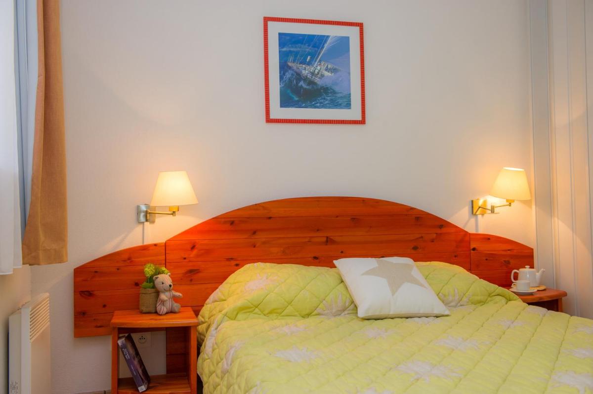 une chambre avec un lit avec une tête de lit en bois dans l'établissement Résidence Goélia Le Cordouan, à Soulac-sur-Mer