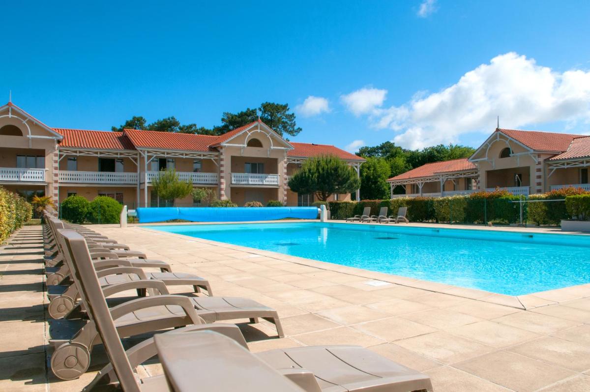- une piscine avec des chaises longues en face d'une maison dans l'établissement Résidence Goélia Le Cordouan, à Soulac-sur-Mer