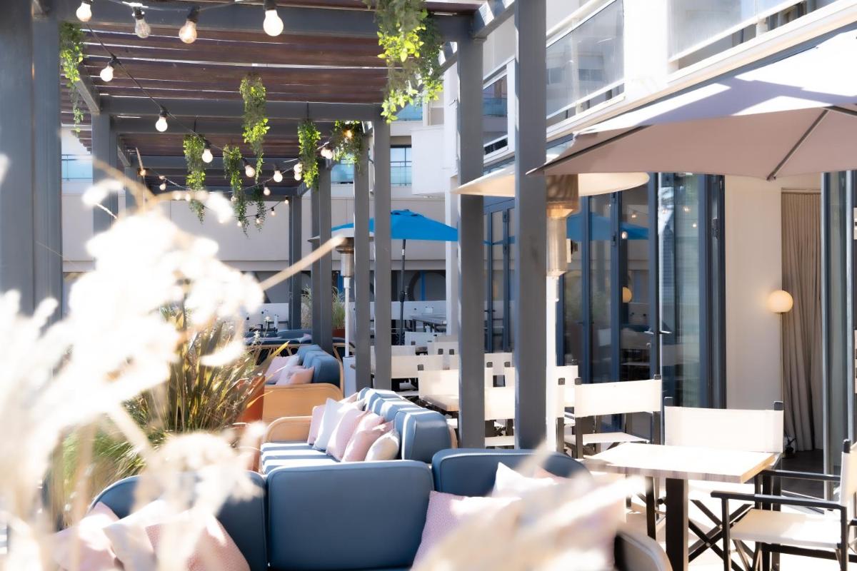 un patio extérieur avec chaises, tables et parasols dans l'établissement Hôtel Mar I Cel & Spa, à Canet 23 autres photos