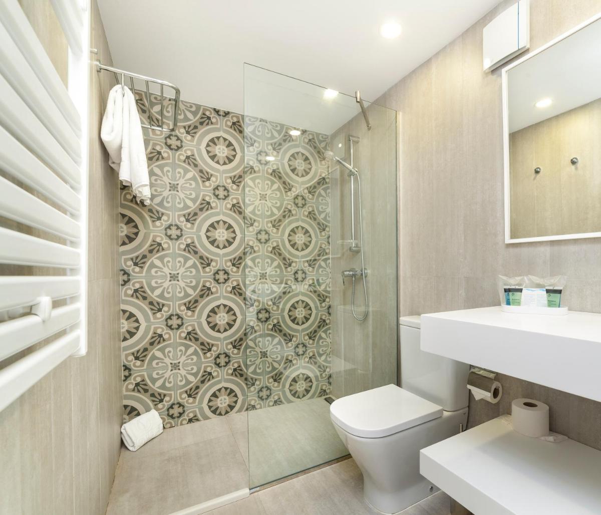 Un baño con inodoro y ducha de cristal. en Hoposa Hotel & Apartaments VillaConcha, en Puerto Pollensa