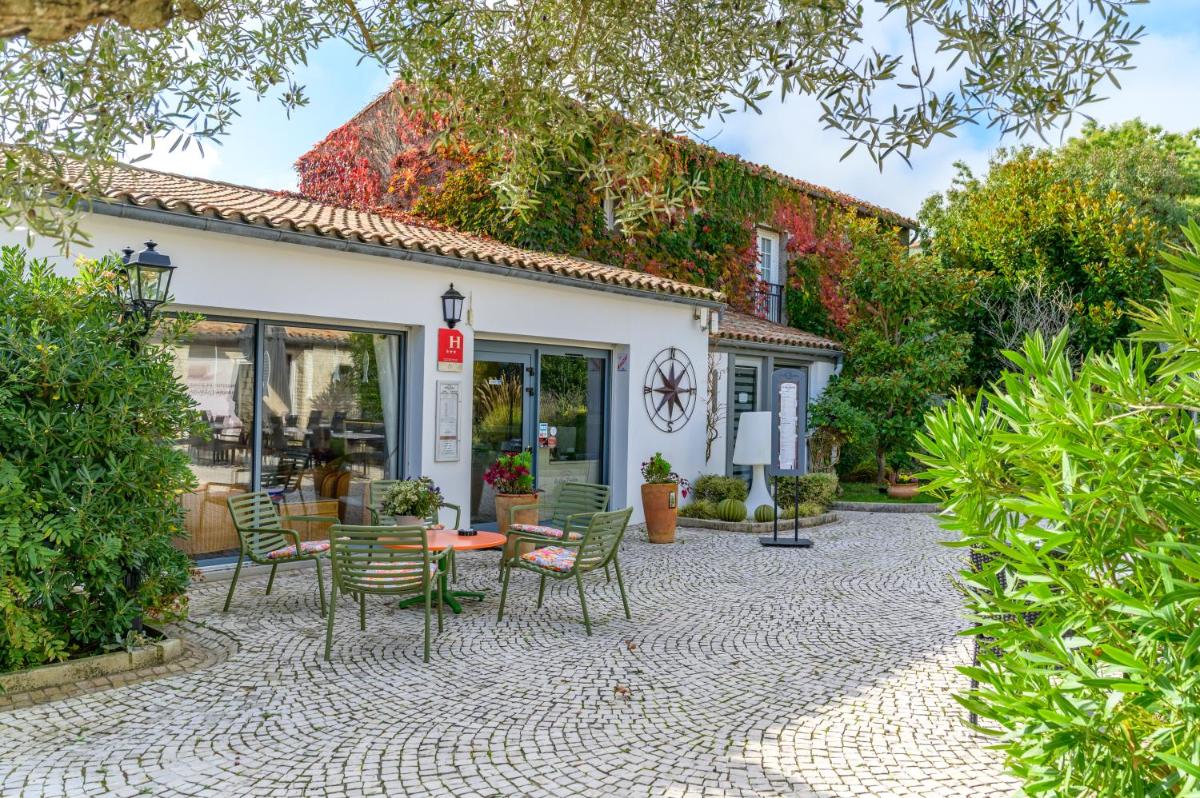 une terrasse avec des chaises et des tables devant un bâtiment dans l'établissement Hôtel Le Peu Breton, à Sainte-Marie de Ré