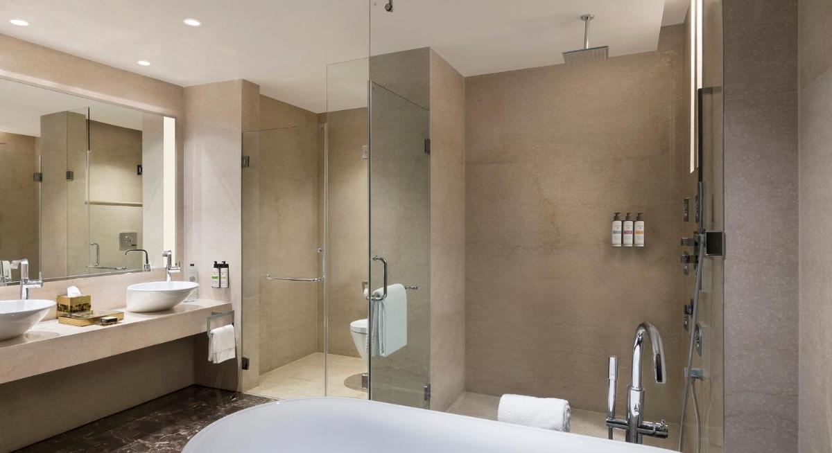 a bathroom with a tub and two sinks and a shower at Pullman New Delhi Aerocity in New Delhi
