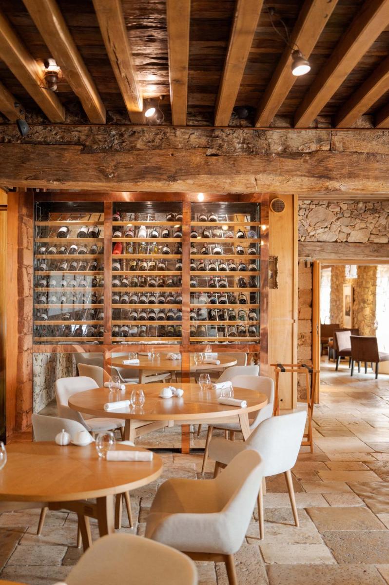 un restaurant avec des tables et des chaises et une cave à vin dans l'établissement Domaine des Etangs, Auberge Collection, à Massignac