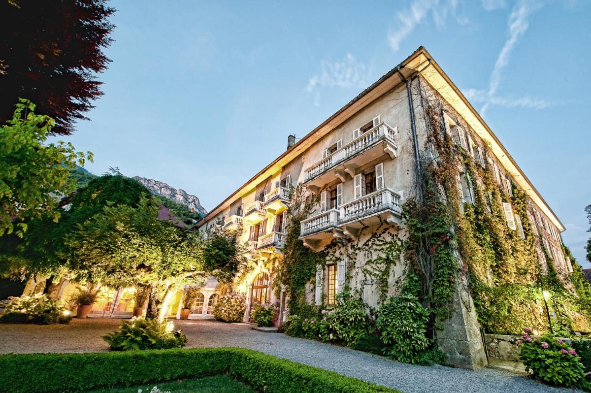 un bâtiment avec du lierre sur le côté dans l'établissement Abbaye de Talloires, à Talloires