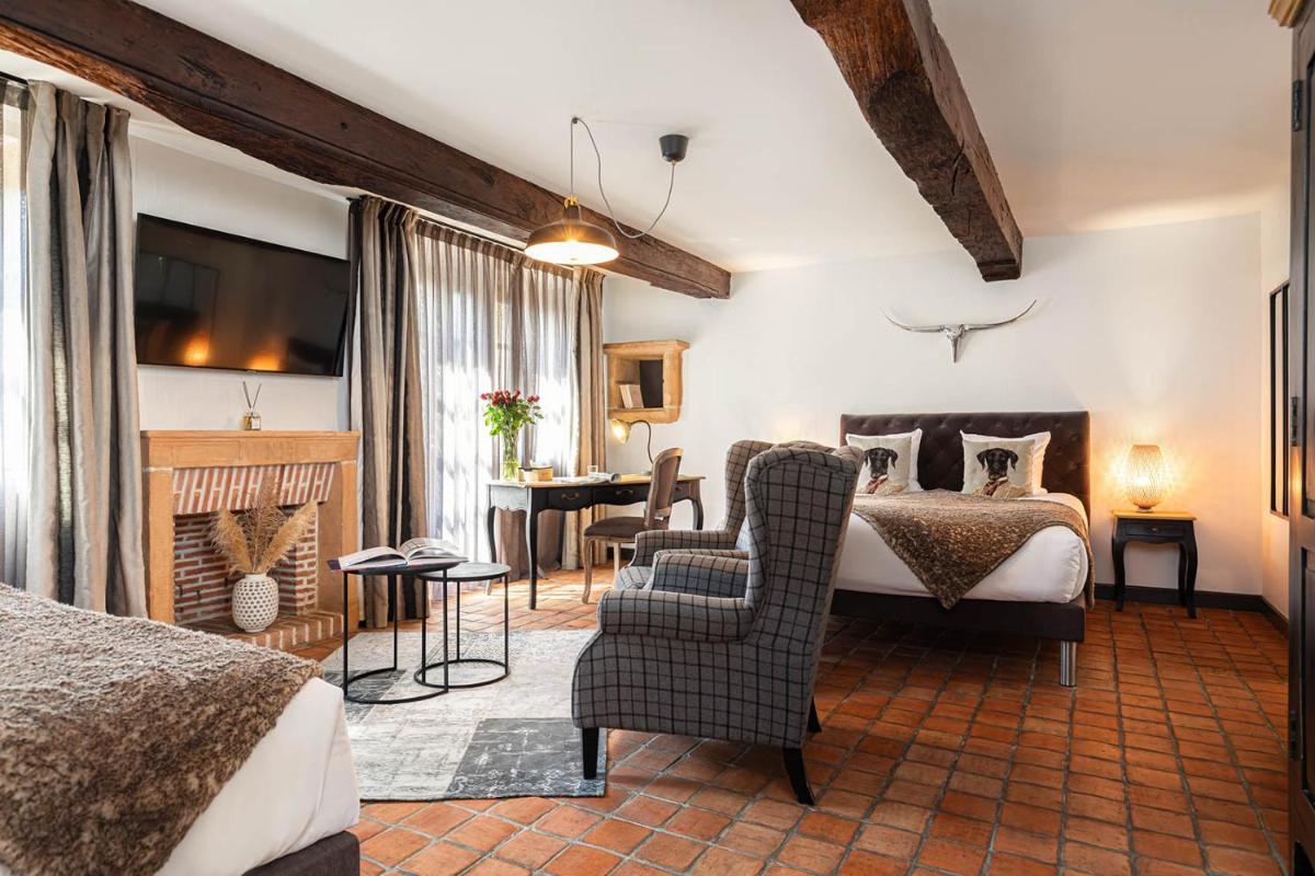 une chambre avec un lit, un canapé et un bureau dans l'établissement Contact Hôtels Le Savigny & Spa, à Blacé une chambre avec un lit, un canapé et un bureau dans l'établissement Contact Hôtels Le Savigny & Spa, à Blacé