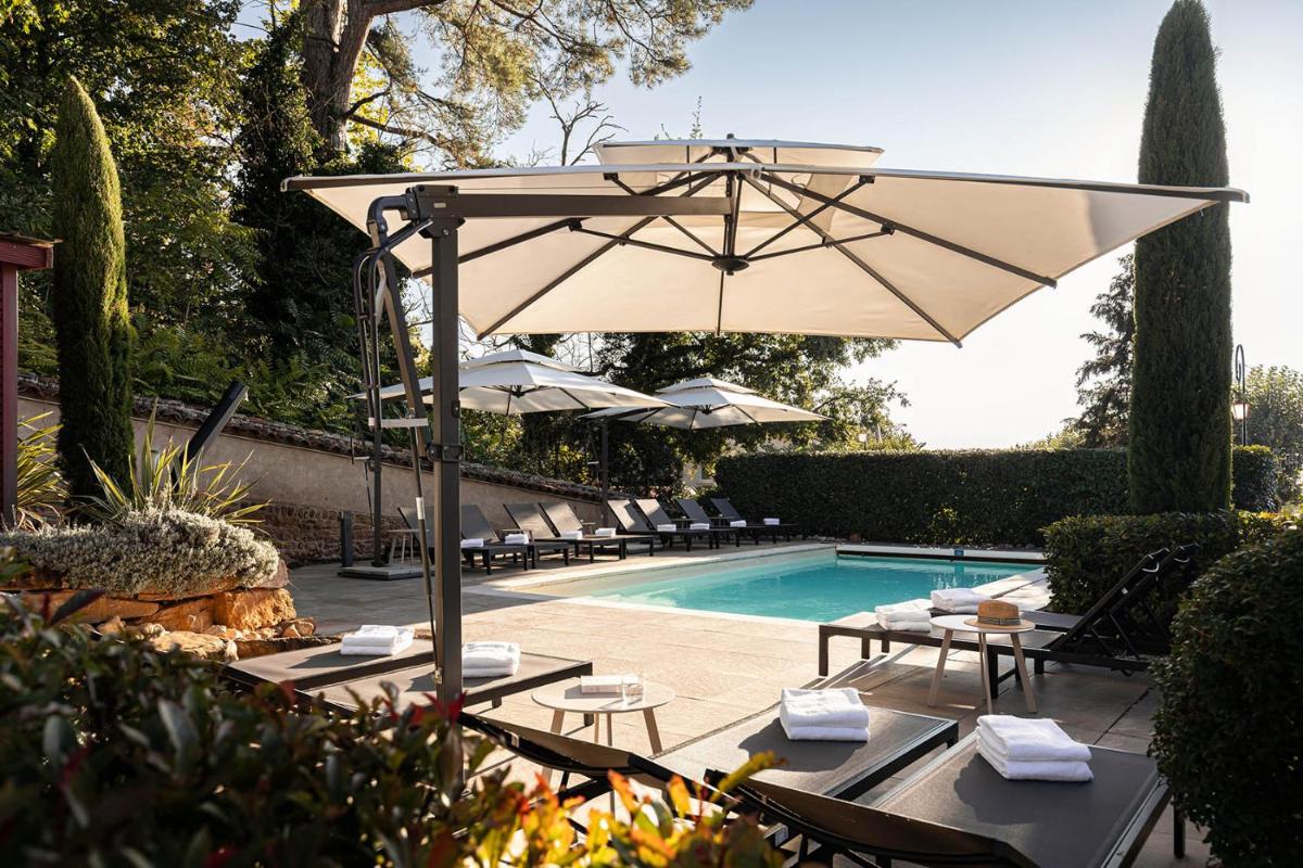 une terrasse avec un parasol et une piscine dans l'établissement Contact Hôtels Le Savigny & Spa, à Blacé une terrasse avec un parasol et une piscine dans l'établissement Contact Hôtels Le Savigny & Spa, à Blacé