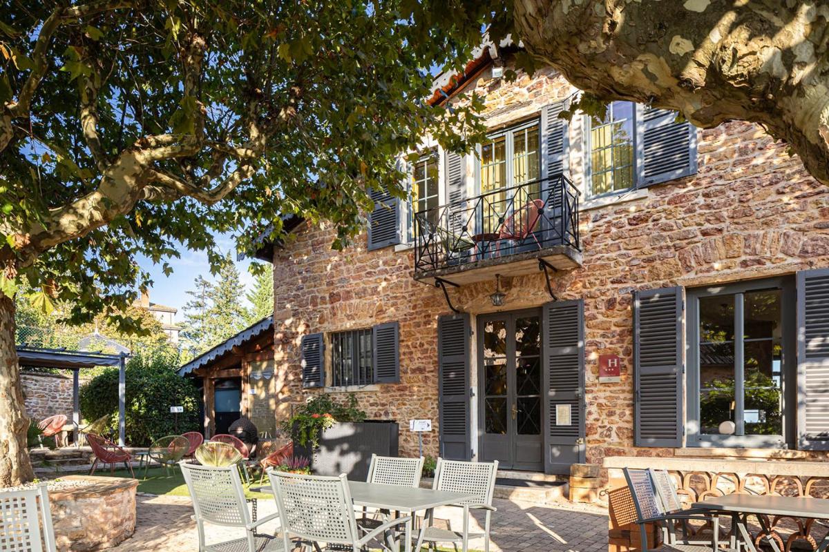 un bâtiment en briques avec une table et des chaises devant dans l'établissement Contact Hôtels Le Savigny & Spa, à Blacé un bâtiment en briques avec une table et des chaises devant dans l'établissement Contact Hôtels Le Savigny & Spa, à Blacé