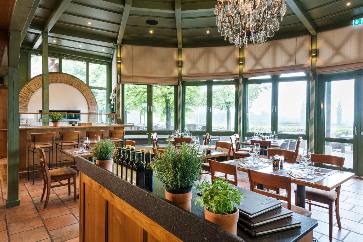 ein Restaurant mit Tischen und Stühlen und einem Kronleuchter in der Unterkunft Hotel Gut Ising in Chieming