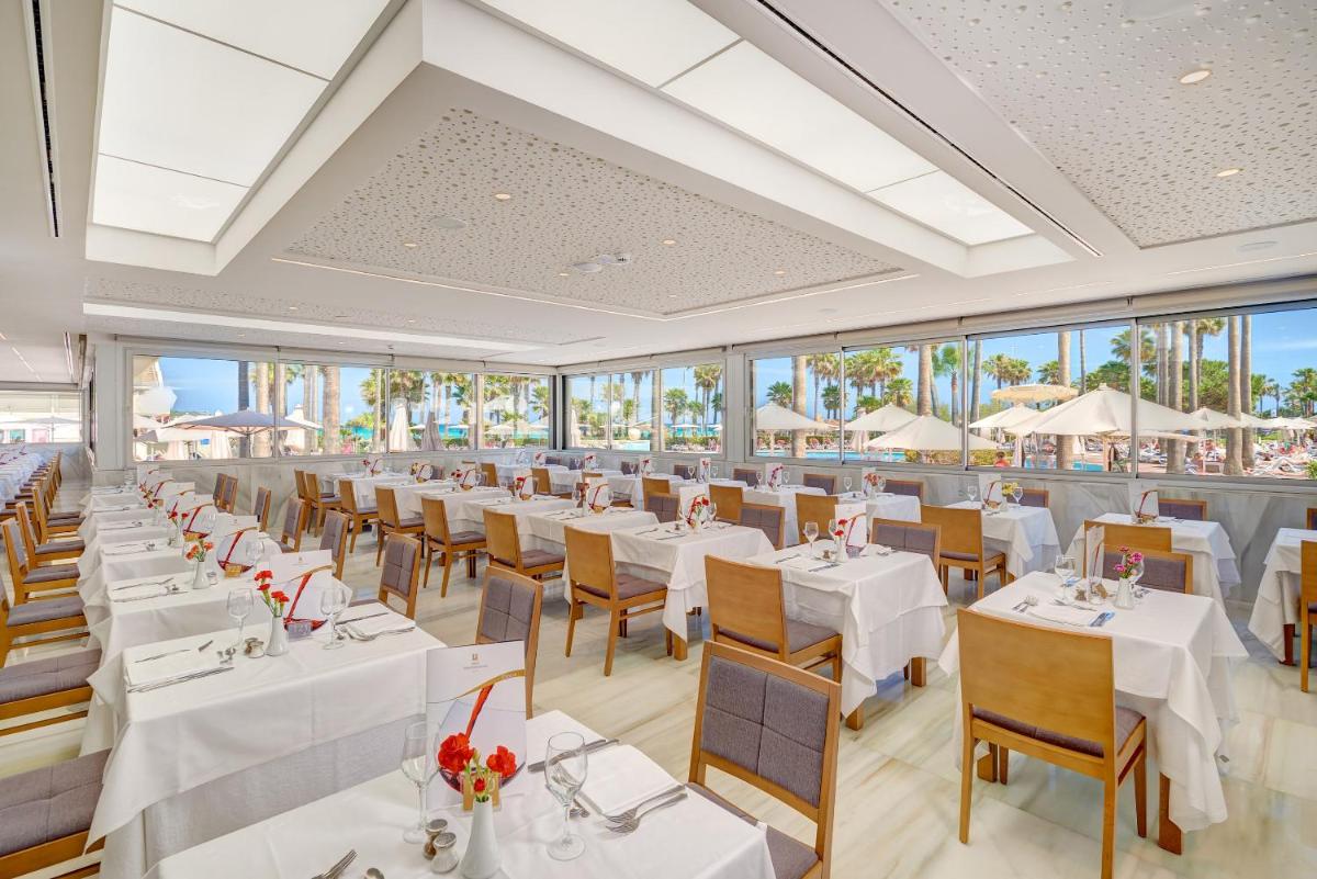 Un restaurante con mesas y sillas blancas y ventanas. en Hipotels Mediterraneo Hotel - Adults Only, en Sa Coma 60 fotos más