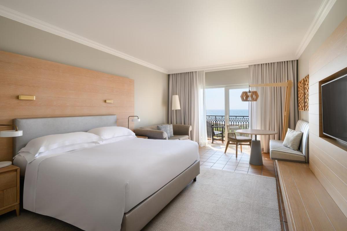 um quarto com uma grande cama branca e uma sala de estar em Praia D'El Rey Marriott Golf & Beach Resort em Praia del Rei