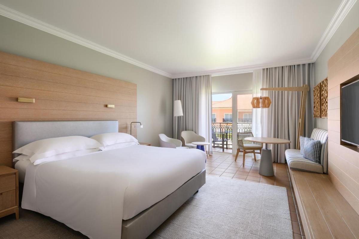 um quarto com uma grande cama branca e uma varanda em Praia D'El Rey Marriott Golf & Beach Resort em Praia del Rei