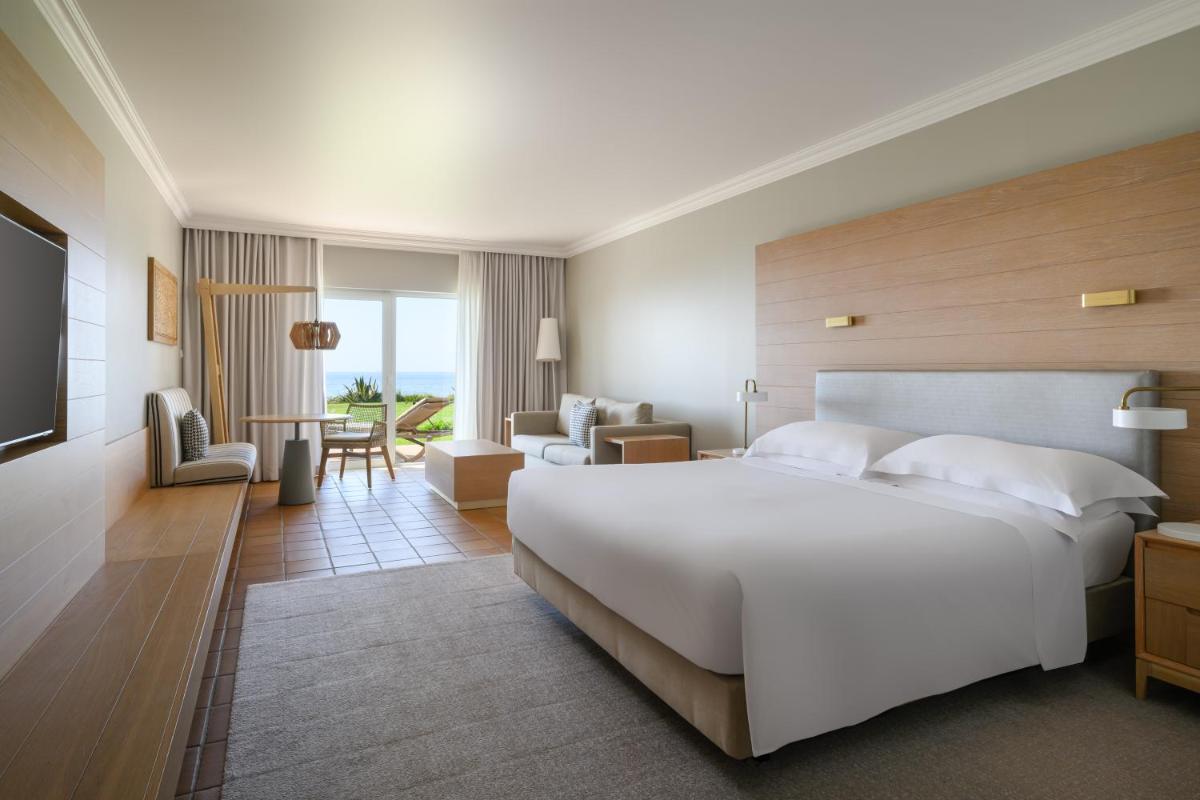 um quarto com uma grande cama branca e uma sala de estar em Praia D'El Rey Marriott Golf & Beach Resort em Praia del Rei