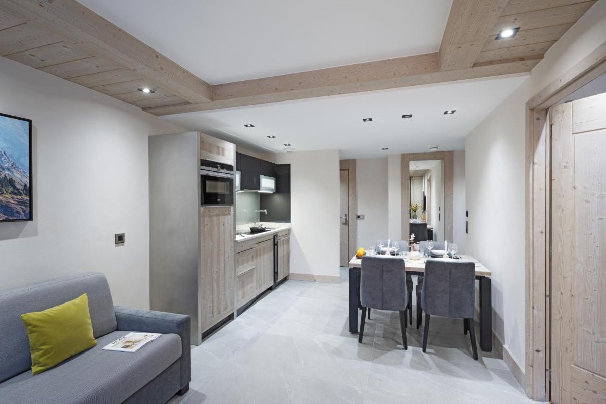 une cuisine et un salon avec une table et des chaises dans l'établissement MGM Hôtels & Résidences - Résidence Chalets de Joy, au Grand-Bornand