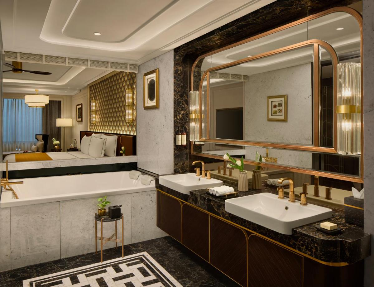 a bathroom with two sinks and a tub and a bed at Fairmont Mumbai in Mumbai