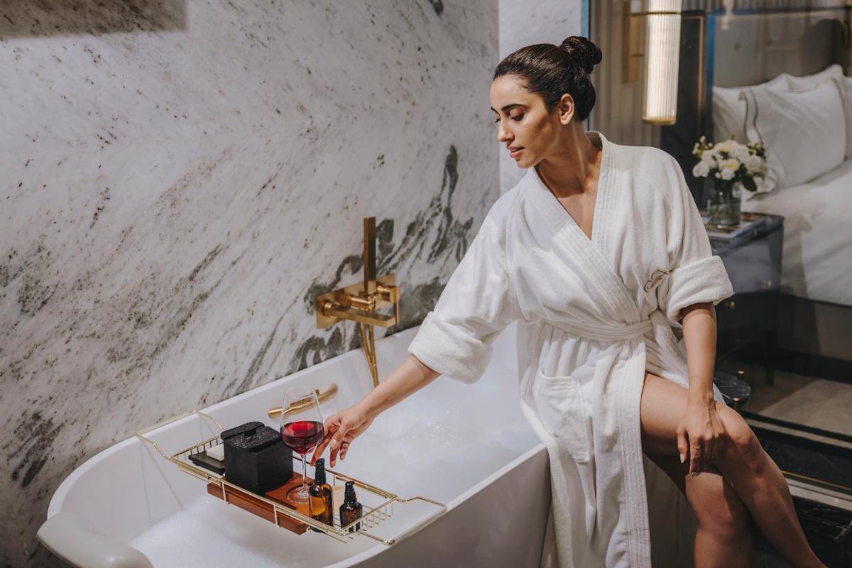 a woman sitting in a bath tub with a glass of wine at Fairmont Mumbai in Mumbai