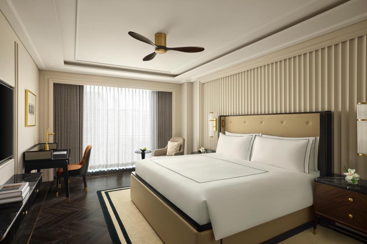 a bedroom with a large white bed and a desk at Fairmont Mumbai in Mumbai