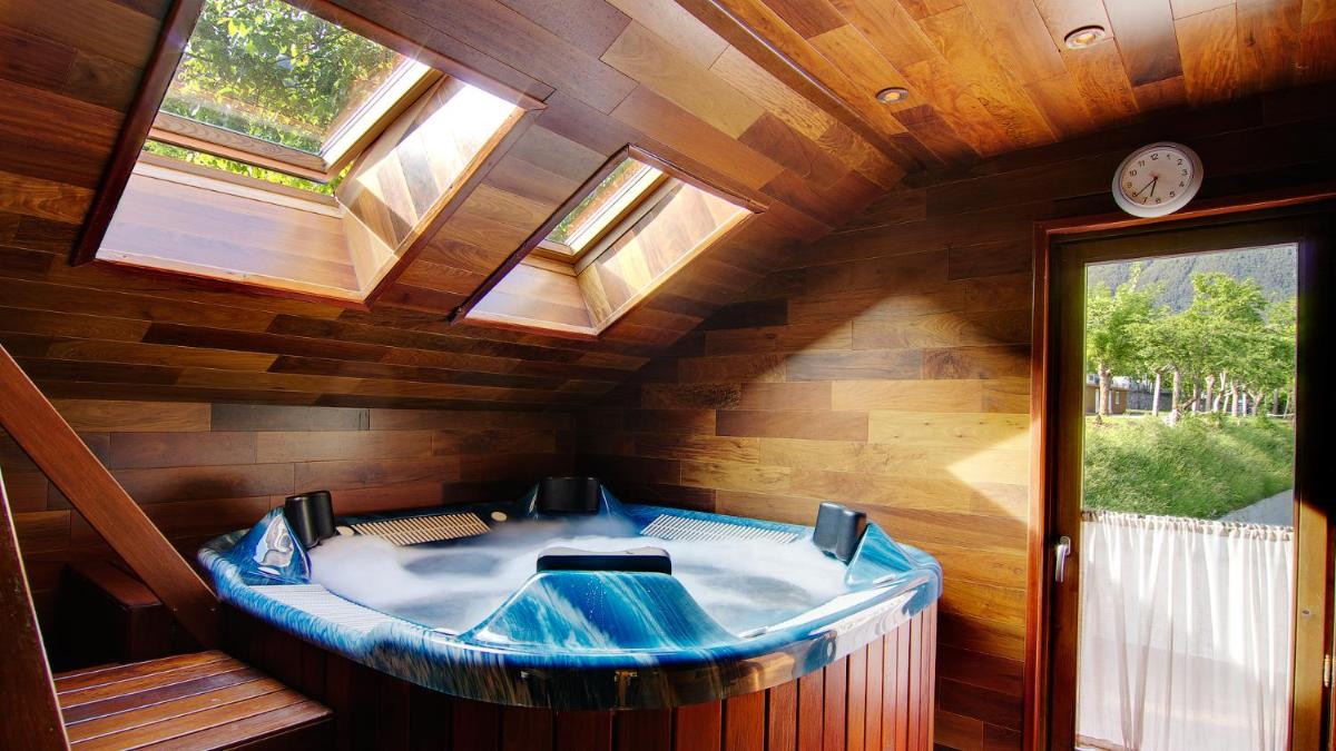 Una gran bañera azul en una habitación de madera con reloj en Silken Ordesa, en Torla