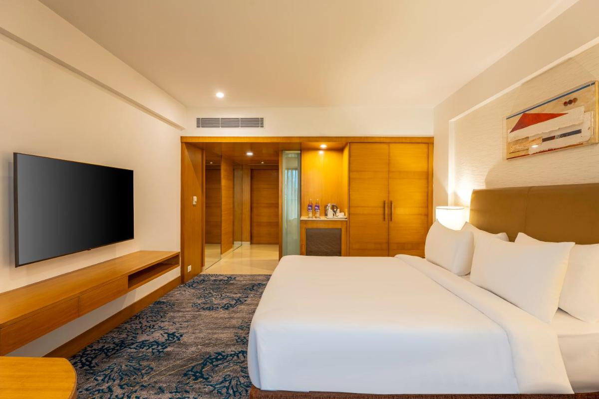 a hotel room with a bed and a flat screen tv at Radisson Blu Hotel Pune Kharadi in Pune