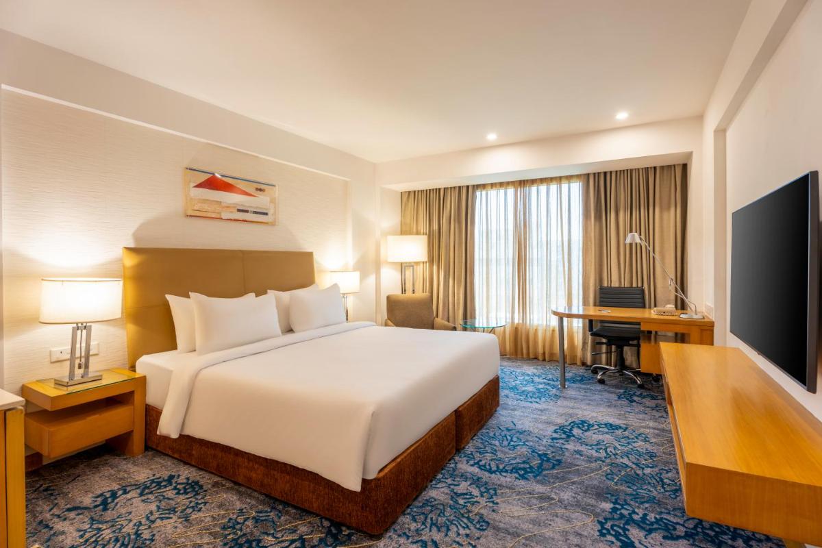 a hotel room with a bed and a desk at Radisson Blu Hotel Pune Kharadi in Pune
