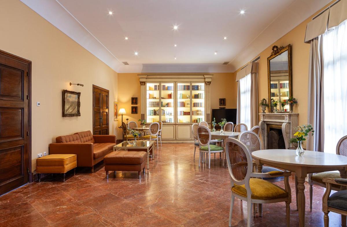 Una sala de estar con un sofá, mesas y sillas. en Villa Jerez, en Jerez de la Frontera