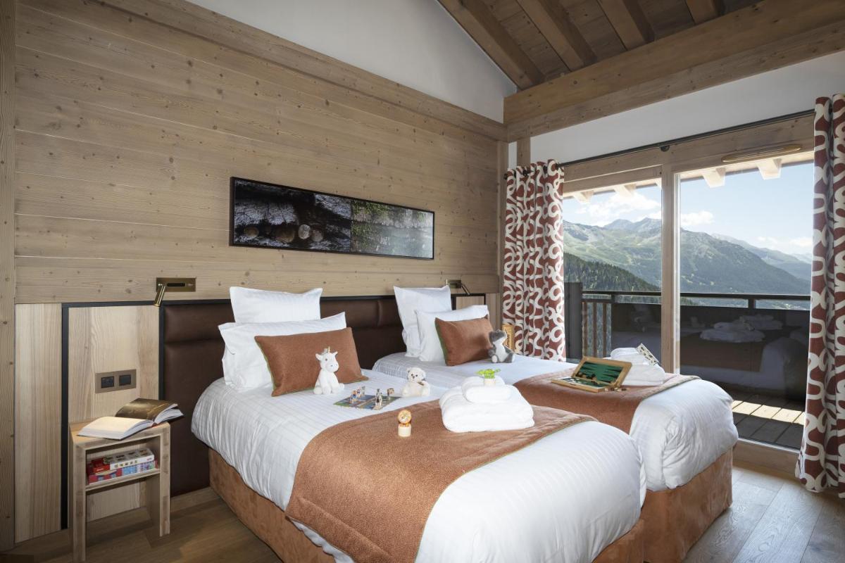 une chambre avec deux lits et une grande fenêtre dans l'établissement MGM Hôtels & Résidences - Hôtel Alpen Lodge, à La Rosière