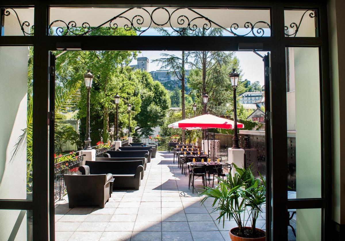une porte ouverte sur un patio avec tables et chaises dans l'établissement Grand Hotel Gallia & Londres, à Lourdes