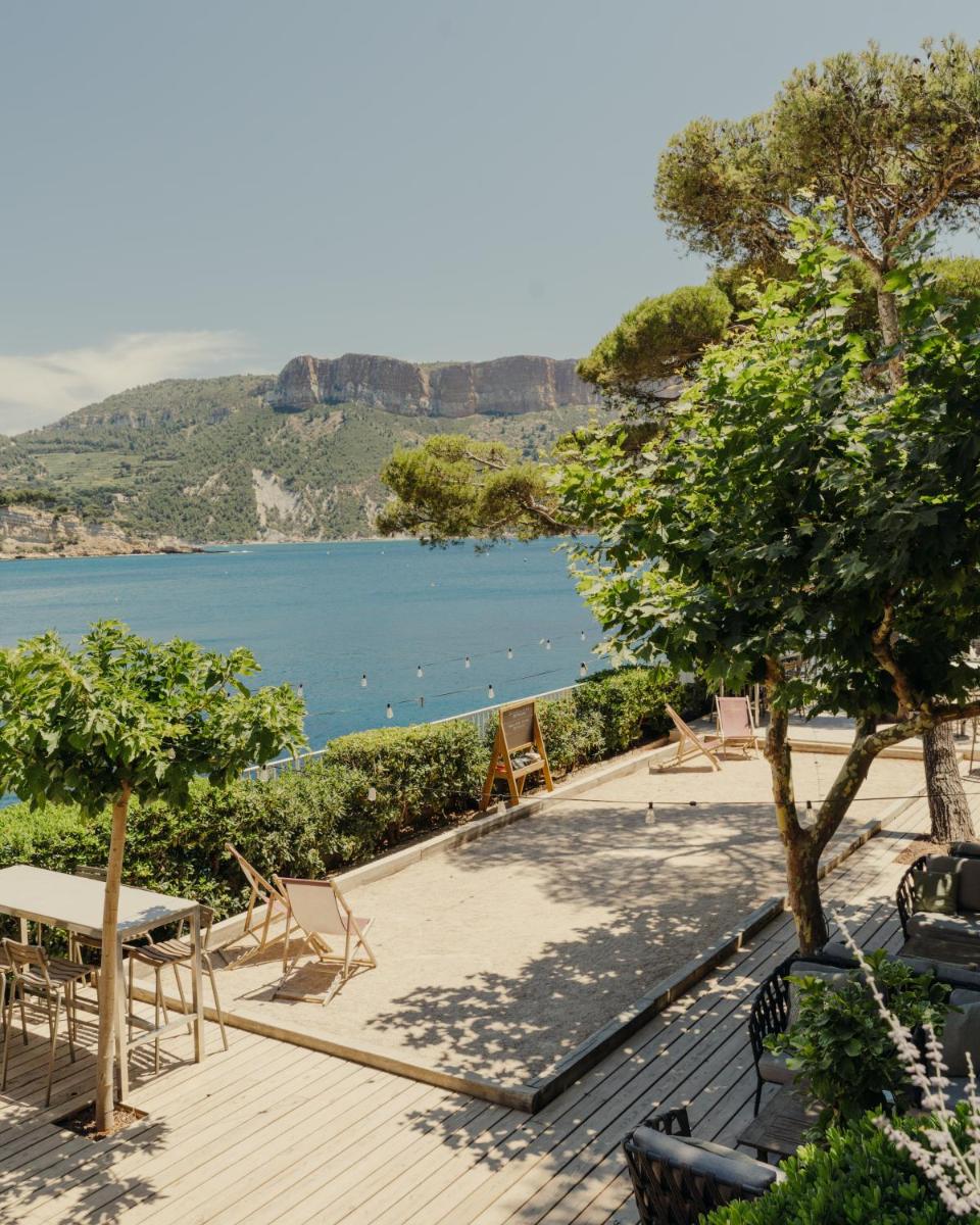 une terrasse en bois avec vue sur l'eau dans l'établissement Hôtel Les Roches Blanches Cassis, à Cassis