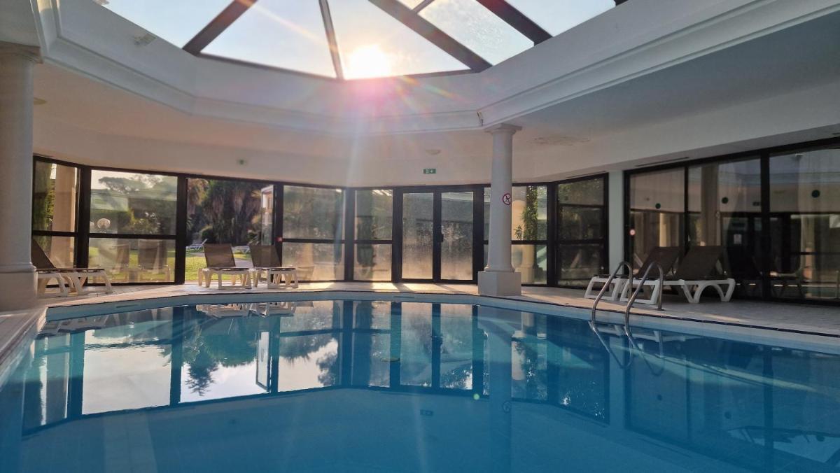une piscine dans un immeuble avec une grande fenêtre dans l'établissement Hôtel Les Jardins De Sainte-Maxime, à Sainte-Maxime