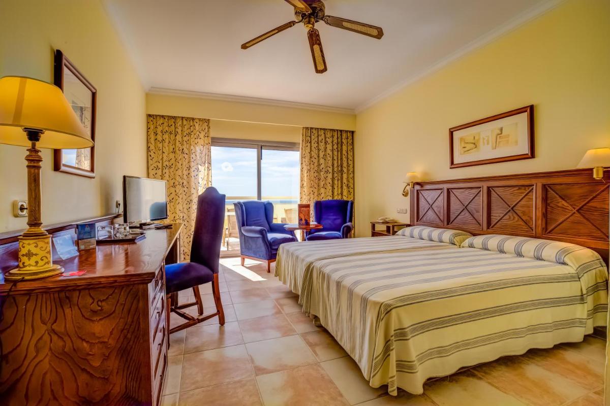 Una habitación de hotel con una cama, un escritorio y sillas. en SBH Costa Calma Palace Thalasso & Spa, en Costa Calma